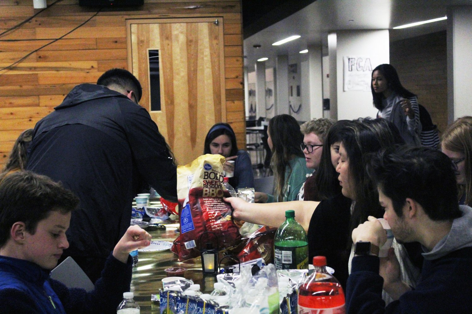 Freshman Neo Kim reaches for more food as he converses with friends at the StuCo club feast.
Photo by Kyla Barnett