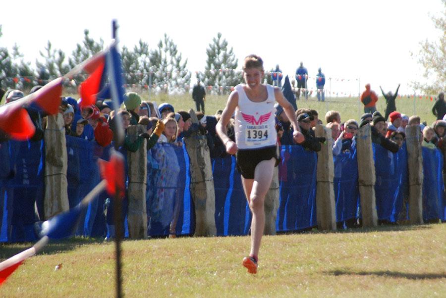 Sophomore Jackson Schroeder crosses the finish line to win the State meet. He was the first boy from Manhattan  High School to ever win. The front runner from Blue Valley, in the last part of the race, kept looking back and we could tell he was worried about us, so seeing that pumped me up, Schroeder said. 