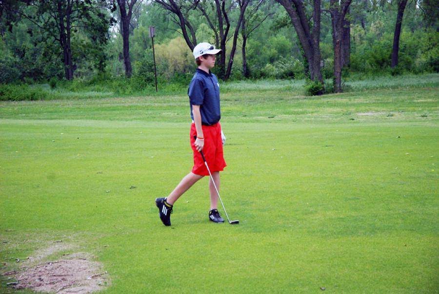 A Junior Varsity Golfer watches his ball after hitting it.