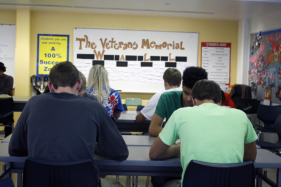 Early fifth hour senior Humanities students read "The Things They Carried" by Tim O'Brein as the Veterans wall they helped create looms over them. The students in teacher Regina Harden's classes wrote the names of friends and family with military connections to honor them.