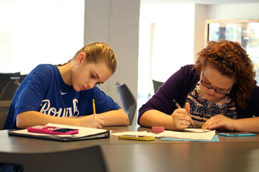 Scavenging for food, sophomores MaKenna Eilert and Hannah Rowley work together to solve a piecewise function in order to earn gravy for their Thanksgiving feast. Math teacher Dedra Braxmeyer's Advanced Algebra II classes were assigned to explore the commons, cafeteria and music department where they solved piecewise functions to earn Thanksgiving inspired foods.