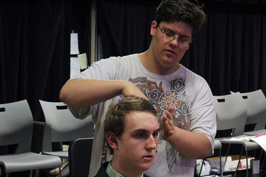 Junior Cody Bell assists junior Isaac Sorell with his hair before a dress rehersal for Guys and Dolls. Bell is a member of the hair and makeup crew for this years fall musical, helping members of the cast as fast as he can while working in the stressful environment.