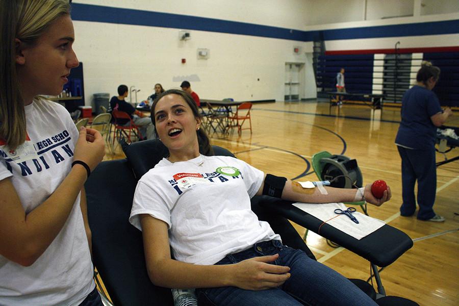 Junior Meg Mankin talks to sophomore Joy Gruenbacher while she gets her blood drawn at the bi-annual Red Cross Blood drive.