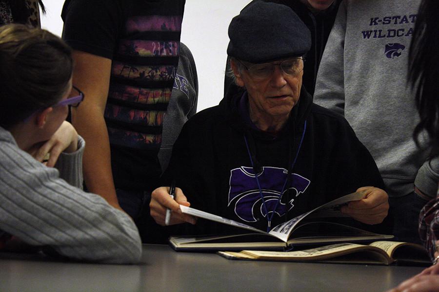 Former MHS stndent Richard Broadhurst flips through his old year book from his seniro year, 1964, with the student publication staff.