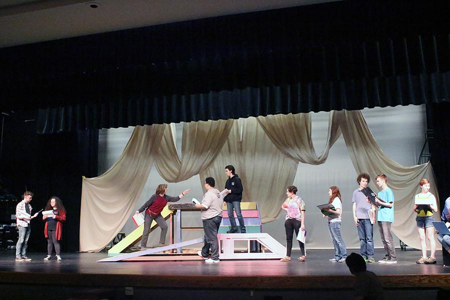 While freshman Jake Wineland and senior Savannah Smith go over their script, freshman Jordan O'Connell and junior Wesley Danielson get acting tips from director Linda Uthoff. Freshman Henry Schinstock, sophomore Erin Hackenberg, sophomore Noah Shirk, freshman Jack Laswell and junior Emma Kellogg observe ready to start receiving advice from Uthoff.
