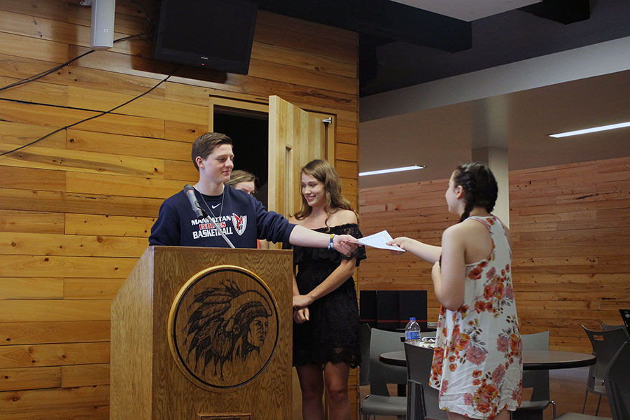 Junior John Ostermann hands freshman photographer Hailey Eilert an award at the journalism banquet