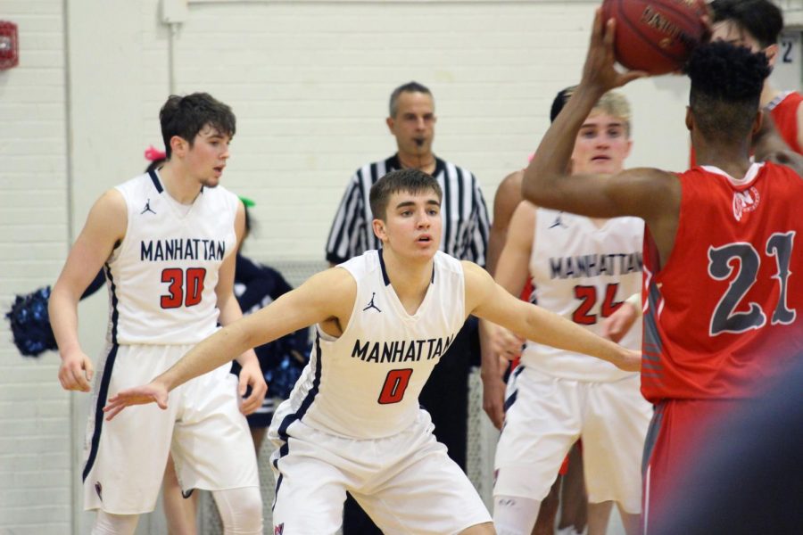 Senior Nate Awbrey defends the opposing point guard with hands high while senior Carson Marsh and sophomore Tyce Hoover stand in help side.