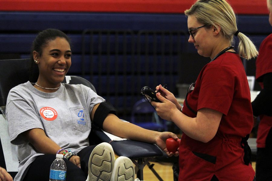 Senior Zoey Blissett smiles while an American Red Cross Nurse is getting her equipment ready for Blood Drawing. The blood drive on Nov. 6 gave students the opportunity to donate their blood to benefit others, after donating blood students were treated to iron-packed snacks like oreos. 