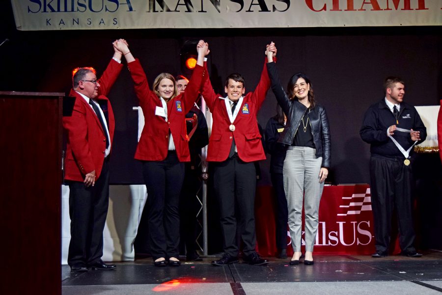 Sophomore Dominic Palmieri raises his arms in the hand after accepting his gold medal at the Skills USA Kansas Championship. Palmeri took first place with a gold medal ranking in the customer service competition. 