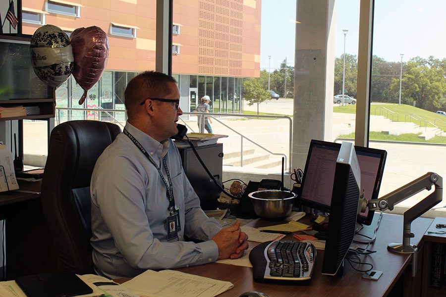 Dorst works on his computer while on a phone call in his new office. While he enjoys the new location for now, he also misses his old office, which allowed him to see student interaction that gives MHS what he calls its pulse.