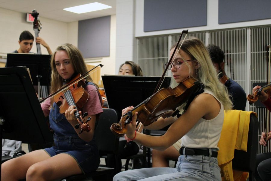 Seniors Grace Hart and Liz Efken practice their Shostakovich piece with their violas as they wait for director Nate McClendon to arrive for class. The orchestra began rehearsing earlier in the week in preparation for the day when they must play it completely by memory.