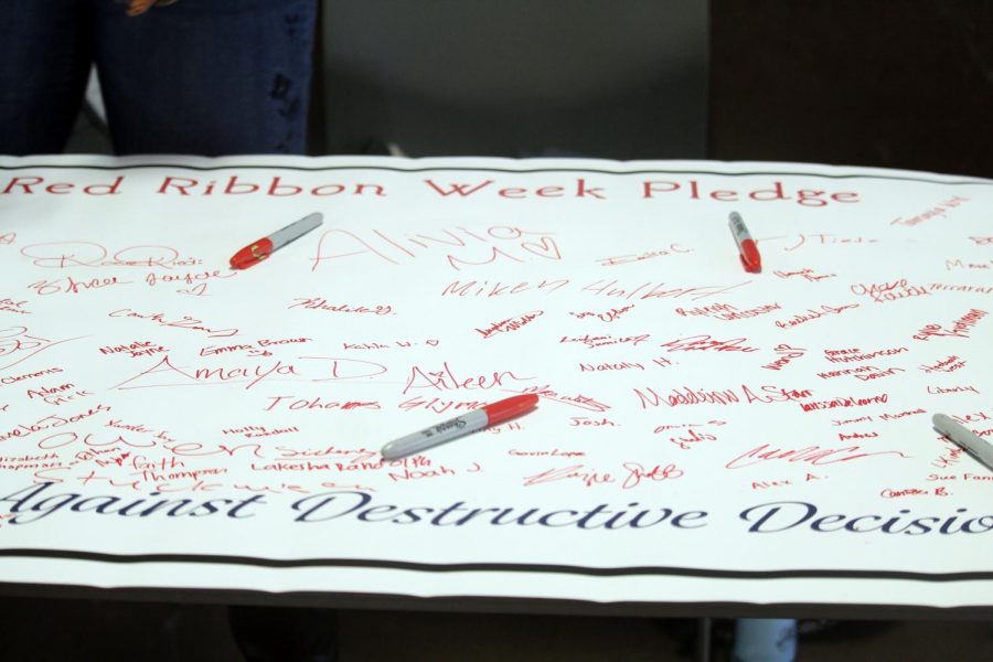Signatures of students who pledged to SADD's cause rest on their poster as other fill in the spaces with their names. The pledge was part of Red Ribbon Week, an event meant to highlight the importance of safer living in teenagers. 