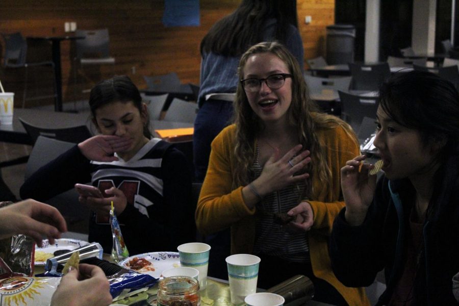 Senior Macy Hendricks laughs with her friends at the StuCo club feast as she enjoys her food.