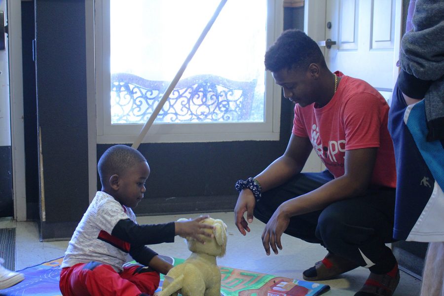 Junior Caleb DeLoach and a child from the Flint Hills Job Corps play with a stuffed toy after IPS delivered gifts to the group after Christmas.