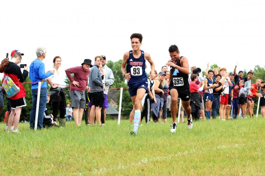 Junior Aidan Starling passes junior Trevor Cain from Washburn Rural just before crossing the finish line at the cross country Manhattan Invitational on Sept. 4. Starling finished in 12th place. Photo by Julianna Poe