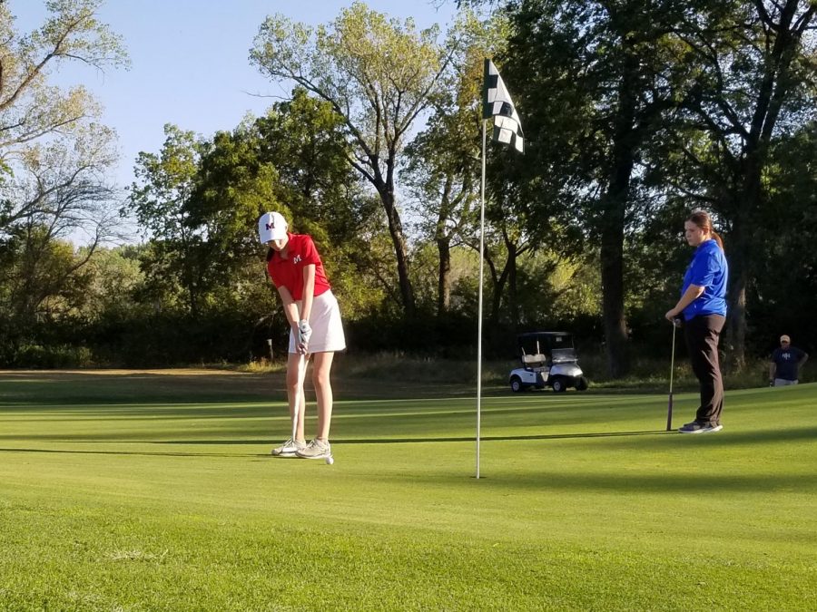 Freshman Ruby Wendt putts out on her last hole, ending with a 114 at the Manhattan Invitational on Monday. The Varsity girls golf team placed third overall as a team. Photo by Julianna Poe