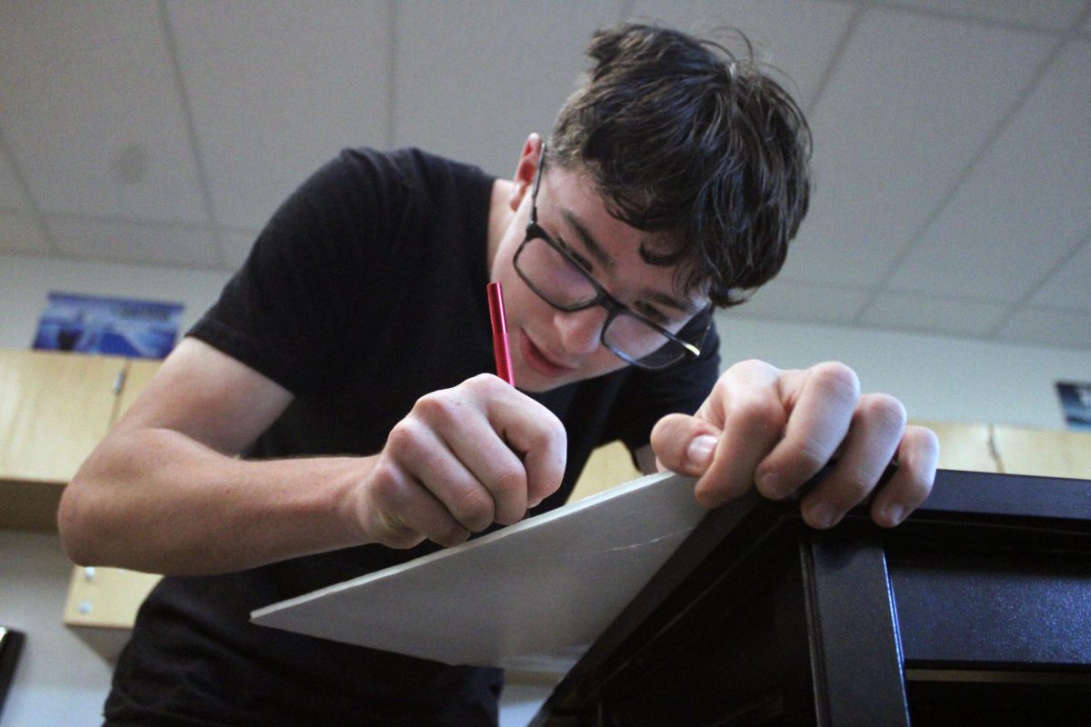 Cutting away Sophomore Jonathan Brown cuts into styrofoam to make a new plane after discovering a fault in his first plane. After finishing the wiring on this plane he and Dexter Schmidt did a test flight and it crashed immediatly and needed to be repaired again.