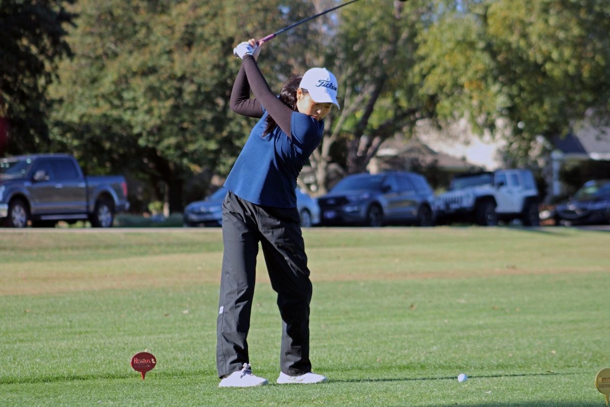 Swinging for success. On October 20th, 2025, Hesston, Kansas, hosts the annual girls golf state tournament, where Manhattan High School proudly participates. Senior Jessica Kim lifts her club high, ready to send the golf ball soaring into the sky.