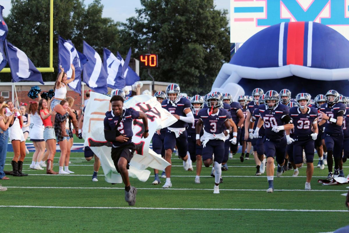 Photo 1:Hyped up. Manhattan Highschool hyped up before the game against Hays Highschool. Manhattan Highschool was running out of the tunnel hyped to play a good game against Hays.