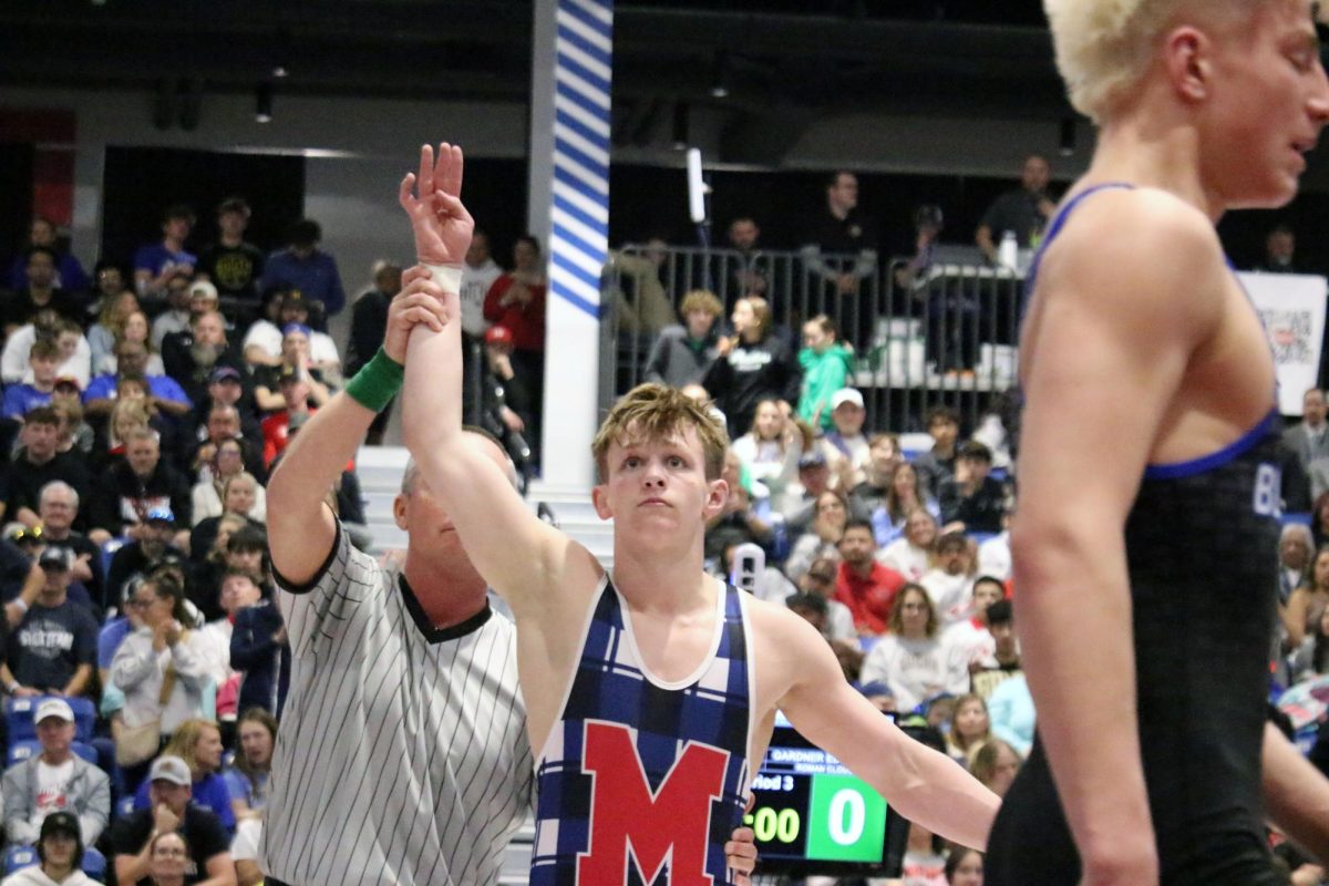 Four-peat Senior Caeleb Hutchinson holds up four fingers as the referee raises Hutchinson's arm in triumph after his State finals match on Feb. 28. The four fingers represented the four individual State titles Hutchinson has won over his four years of high school, a feat that very few people can say they've accomplished.
"The more times it happens, the more I feel relaxed," Hutchinson said. "So I mean, there was definitely a lot of pressure, but not as much as, if it was the first time."
