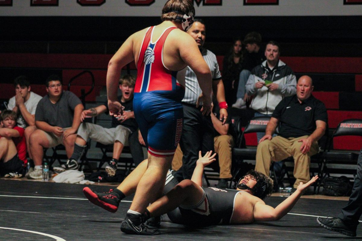 Stare down Sophmore Tucker Horton stands above his opponent as he stares him down during the Varsity wrestling dual against Great Bend on Dec. 4.