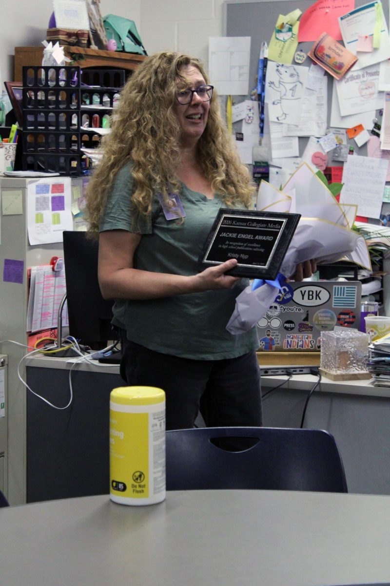 Gratitude. Media and Publications teacher Kristy Nyp tearfully listens to the heartwarming speech made for her for winning the 2026 Jackie Engel Award. The nominations for this award are put into the Kansas Scholastic Press Association (KSPA) website through applications. The announcement was made on Apr. 23, during the 5th hour period.