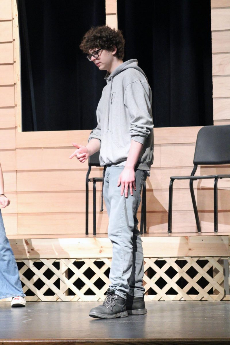 Finger gun. Sophomore Michael King works through the unmemorized lines with his co-actors for the Manhattan High School spring play, Proofs on the tech day. This rehearsal day is for the actors and crewmembers to get together at the school and fix lines, make cues, try costumes and more. The tech day was on Apr. 26.