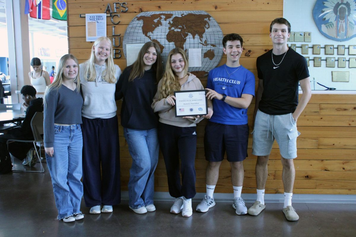 All together. A group of students in AFS take a photo together to recognize this moment of handing over an award of appreciation and recognition to the principal of MHS, Michael Dorst. The award us being given as a thank you for hosting and teaching these exchange students, especially the two who are funded. This award giveaway was on Apr. 27, during first lunch at the AFS club sign. 