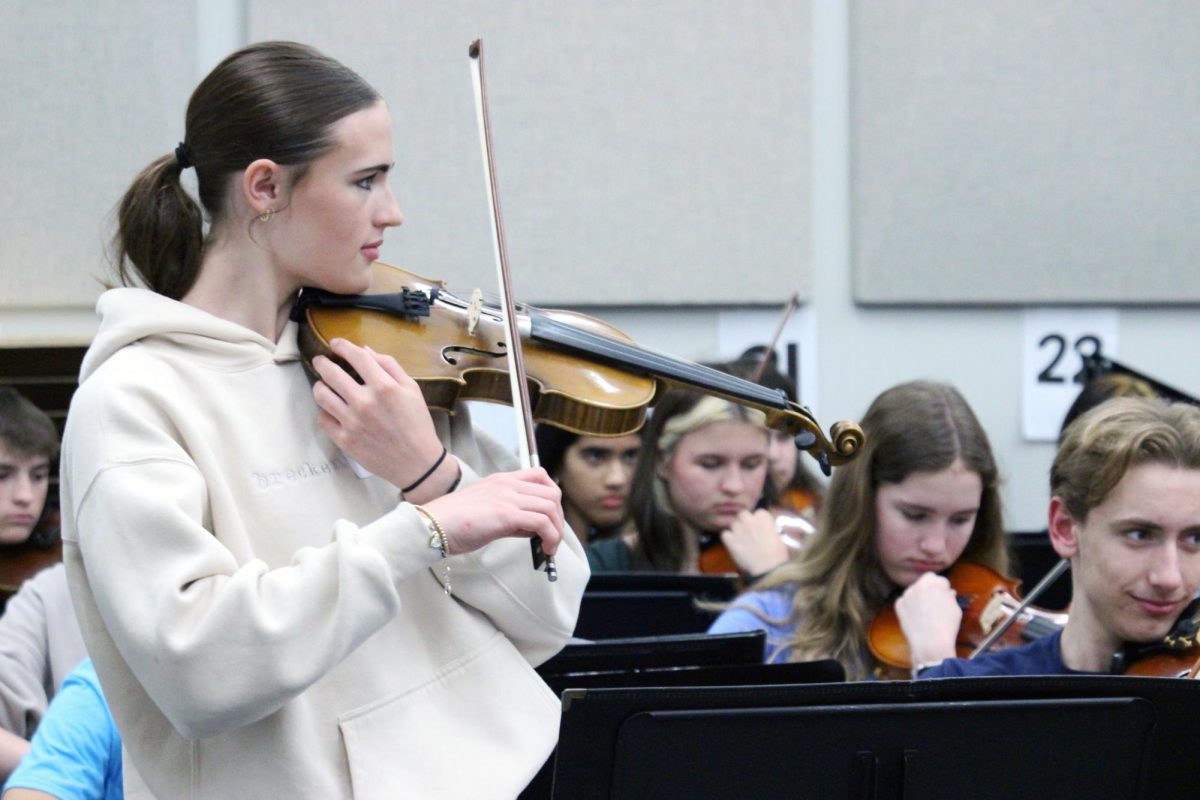 Tuning note. Junior Natalie Blanc bows the tuning note for the ensemble made up of both Anthony Middle School string players and Manhattan High School players. The MHS Symphonic Orchestra is visiting the middle school strings to have fun and to encourage them to join the Symphonic Orchestra when they move up to the high school.