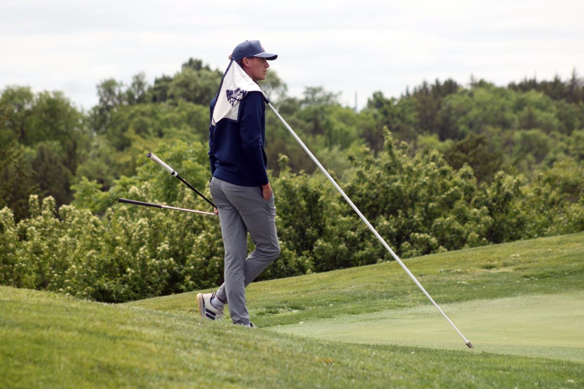 A shoulder to lean on. Senior Cooper Graham picks up the flag from the hole on the green to give way for the other teams’ balls and his own to make it into the hole. This was during the Substate Tournament that the Manhattan High School Varsity Golf Team attended on May 20, and it was held at the Manhattan Country Club.
