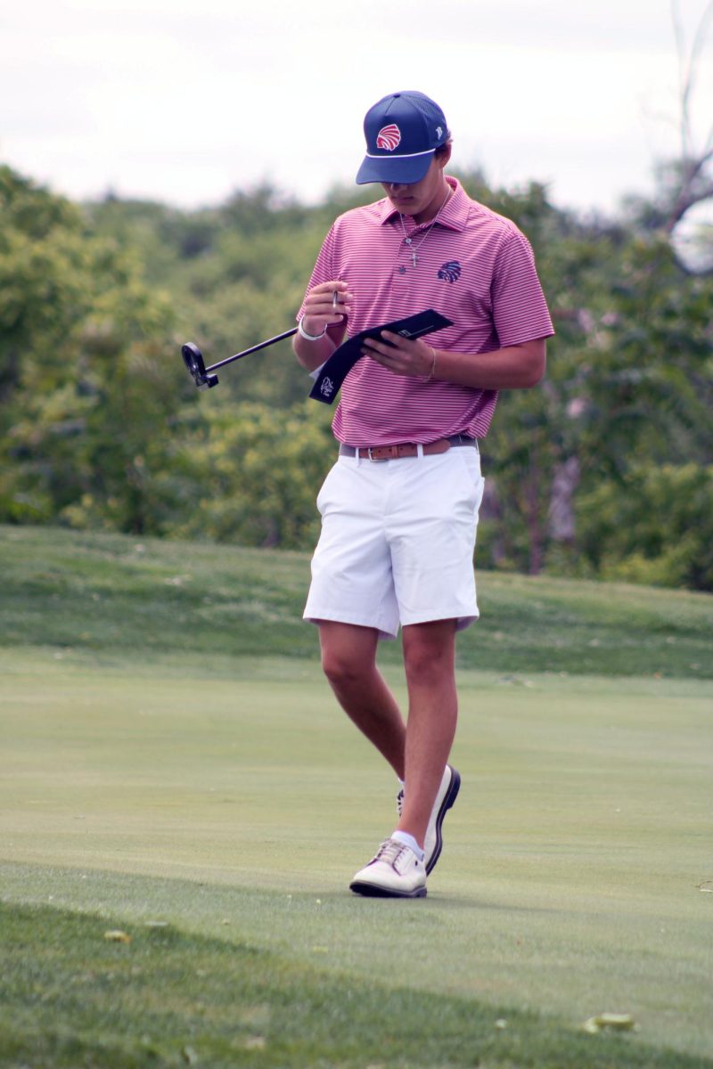 Book and cover. Senior Cade Cochran checks his numbers and writes new ones into his little booklet, keeping track of each swing during the Golf Substate tournament. The Manhattan High School Varsity Boys Golf Team had competed in this event, which was held at the Manhattan Country Club on May 20.